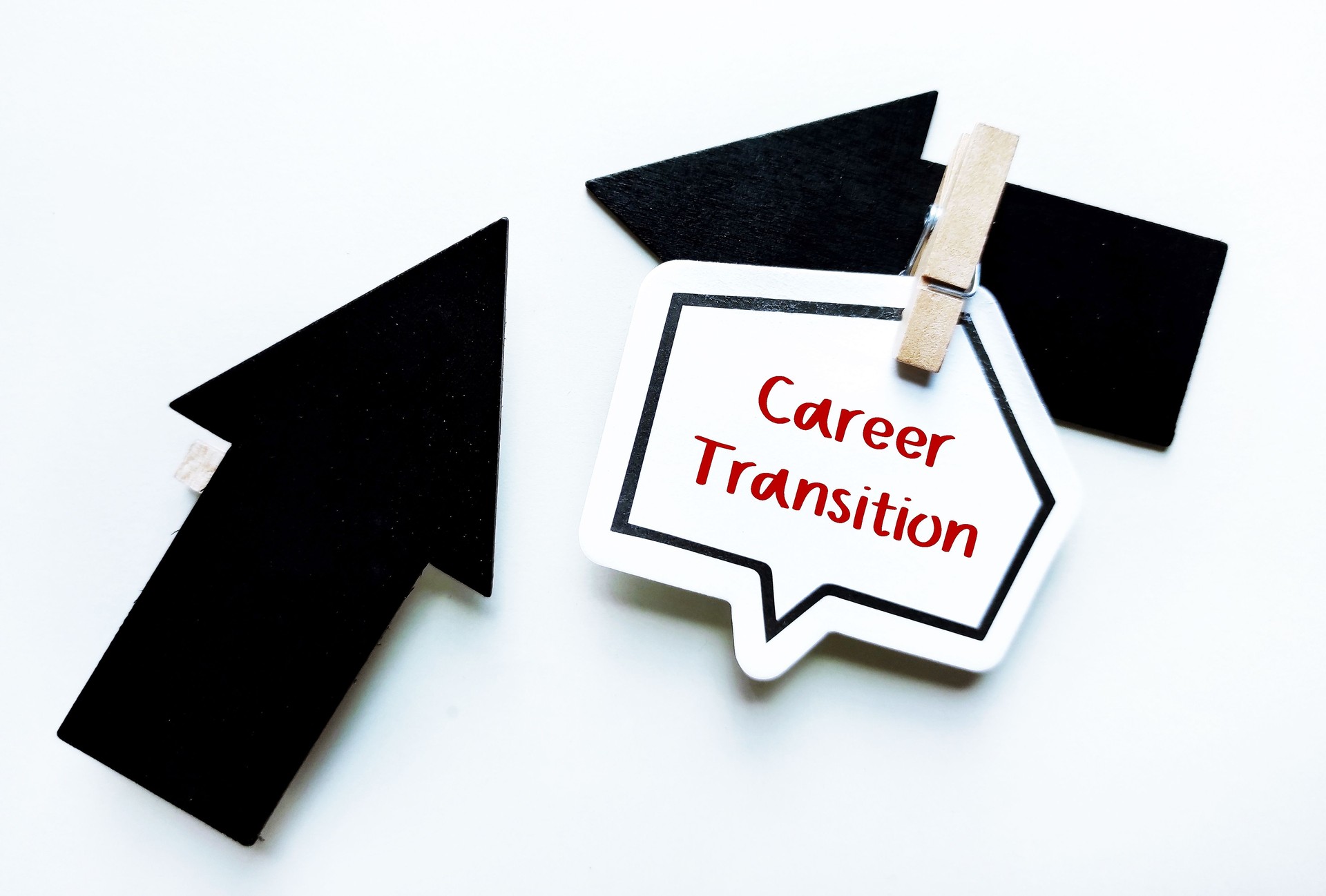 Direction arrows clip with note paper written CAREER TRANSITION, means changing jobs or being relocated or jumping into a new career, need to overcome fear and get out of comfort zone